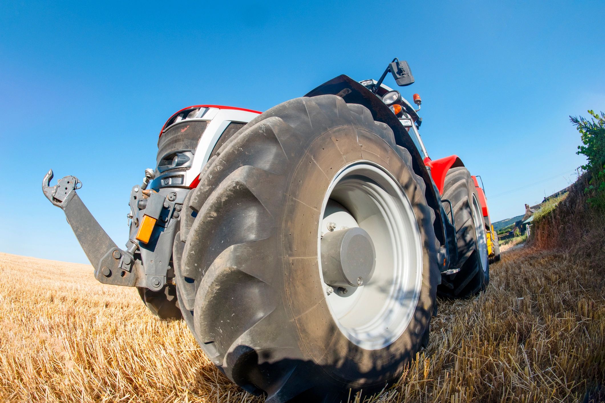 Tractor working open land under a bright blue sky